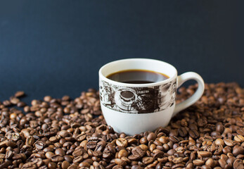 cup with coffee on a dark background and scattered grains of coffee. good morning . kind of sveru. flat lay. place for text. coffee time.
