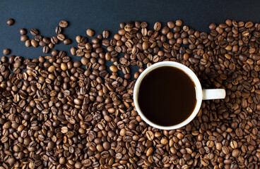 cup with coffee on a dark background and scattered grains of coffee. good morning . kind of sveru. flat lay. place for text. coffee time.
