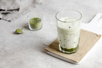 iced matcha green tea with milk and ice on a gray table