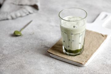 iced matcha green tea with milk and ice on a gray table