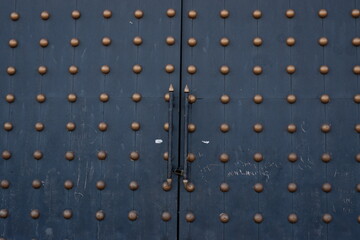 A large black door with embossed dot pattern ornaments