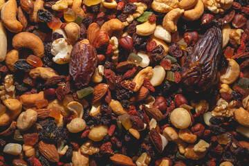 Top view of assorted nuts and dry fruits, including dates, hazel nuts, goji berries, macadamia nuts, almonds and dry fruits.