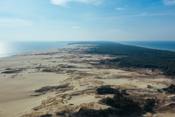 A view from a height of a narrow and long sandy saber-shaped strip of land separating the Curonian Lagoon from the Baltic Sea. Gray sand dunes of the Curonian Spit.