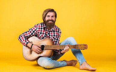 Obraz premium brutal bearded man wear checkered shirt having lush beard and moustache playing the guitar, music