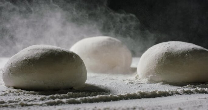 Flour dust falling on dough formed into loafs of bread. Sifting flour in a bakery show. Making of bread. Food and drink close up 4k footage