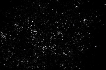 White crystals of sugar scattered on a black surface.