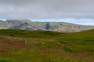 Fototapeta premium Grassy landscape with mountains and meadow near the Black Sand Beach Vik South Iceland