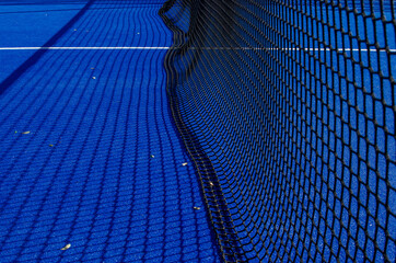 Net of a blue paddle tennis court.