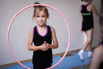 Portrait of little girl gymnast with hoop in gym on training