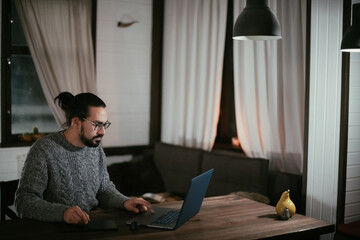 A man draws on a tablet at his home workplace in the evening.