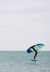 sportsman with wingfoil sailing, in the sea