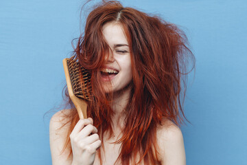 woman with bare shoulders tousled red hair comb blue background