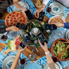 several hands with cellphones taking photos of food at the christmas dinner table