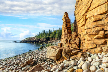 Monument Cove, with its signature sea stack hoodoo, has a beach of granite boulder rocks leading down to the sea in Acadia National Park on Mt. Desert Island in Down East Maine. - obrazy, fototapety, plakaty