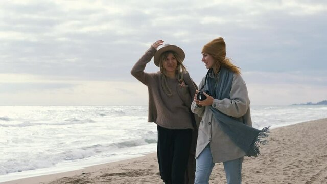 beautiful girls walk near the sea. Woman couple having a good time next to the ocean in cold sunny day 