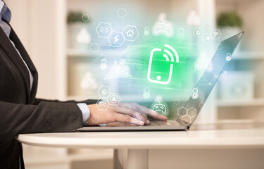 Hands working on laptop with digital icons