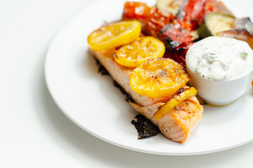 Grilled salmon fillet served with roasted vegetables with cucumber and dill sauce