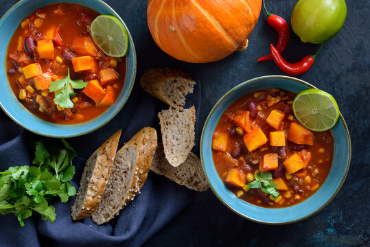 Feuriges Chili con K&uuml;rbis aus der veganen K&uuml;che mit Limette und Koriander&ndash; Hot vegan chili con calabaza from the vegan cuisine with lime and coriander served with slices of a wholemeal roll