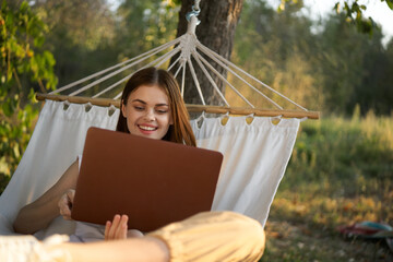 Naklejka premium woman with laptop and lies in a hammock vacation nature freelance