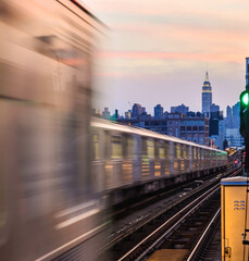 Two subway trains passing each other with Empire State Building in the background.