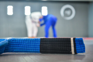 Martial arts blue belt in foreground with people in background.