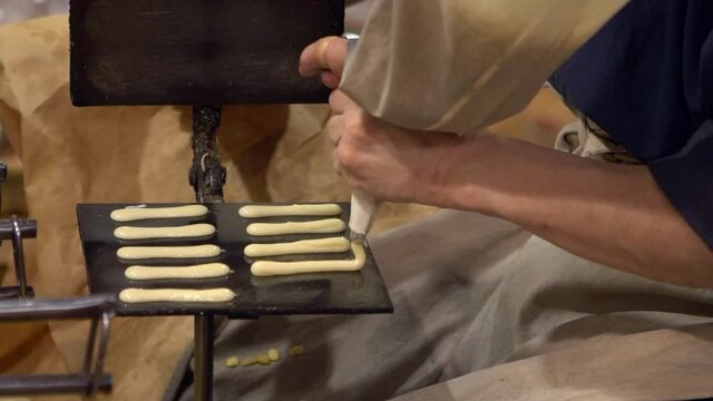 Asian man make craft sweet snack cooking recipe on hot table. Manual industrial cookie make machine. Crispy almond cookies dessert is a street snack popular local people in Japan-Dan