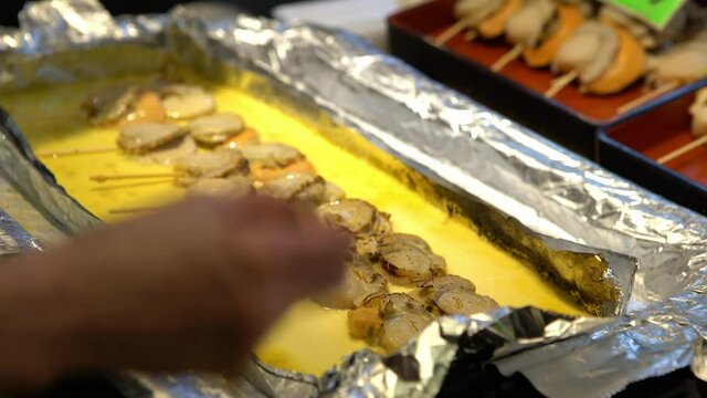 Eating hotate sashimi. Merchants sale deliceous scallop in Nishiki fish market. Famous asian raw seafood meal. Traditional menu food and healthy eating-Dan