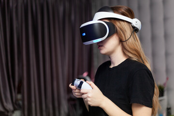 young woman in virtual reality helmet with gamepad joystick playing © ilya