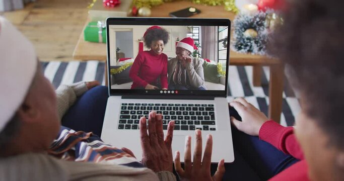 African american mother and daughter using laptop for christmas video call with family on screen