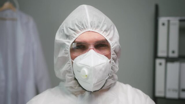 Close-up of overworked doctor or researcher dressed in protective suit ppe mask in laboratory in hospital, female nurse wearing medical uniform, portrait of tired woman chemist in safety glasses. 