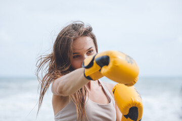 girl practices boxing beach background.  Young woman kickboxer trains  on the beach at sunrise....
