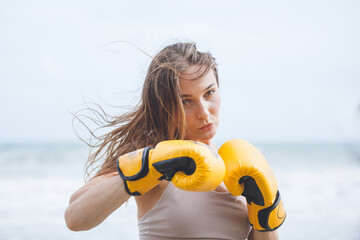 girl practices boxing beach background.  Young woman kickboxer trains  on the beach at sunrise....