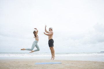 Fototapeta na wymiar fitness, sport, and lifestyle concept - couple making yoga exercises on beach, Man and woman doing yoga exercise on the beach.