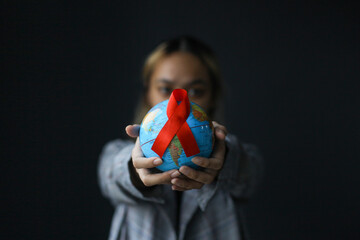 Aids red ribbon and globe in woman's hands for World AIDS Day.