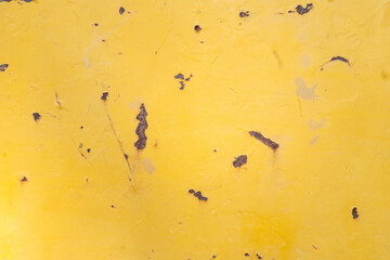 Yellow painted metal with rust and distress .