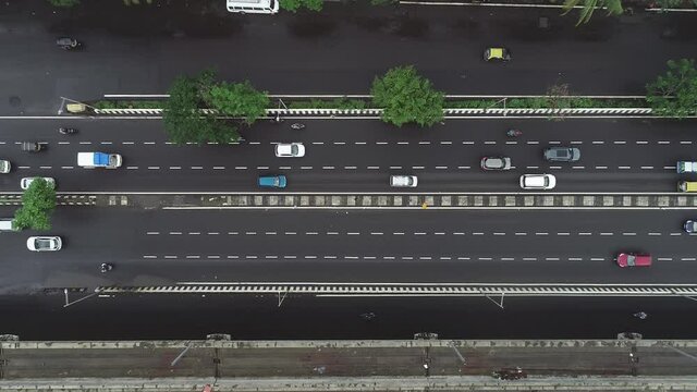 Aerial view drone shot of a busy six-lane Highway with fast-moving vehicles in a organised manner or following lane discipline in Metropolitan or MegaCity area during a broad daylight