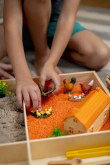 Touch drawer with rainbow rice inside. Children hand touch the texture. Montessori material concept for toddlers.