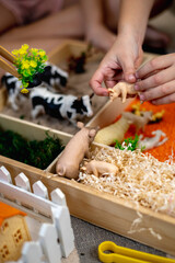 Touch drawer with rainbow rice inside. Children hand touch the texture. Montessori material concept for toddlers.