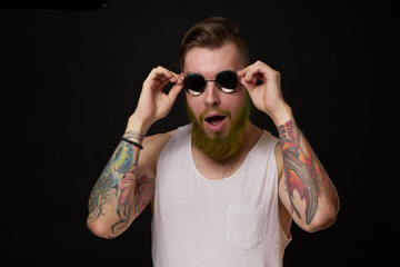 handsome man with tattoos on his arms fashion sunglasses dark background