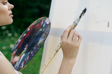 Obraz premium woman artist paints palette easel nature drawing