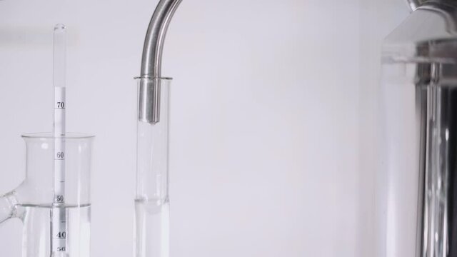 Moonshine machine close-up. Dripping drops of alcohol into a flask with an alcohol meter. Slider movement from top to bottom