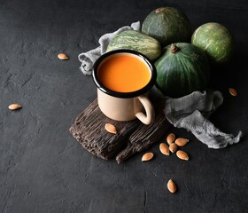 Fresh pumpkin juice in a mug with pumpkins on a black background. Top view. Rustic style