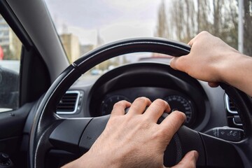 One hand of the driver presses the signal, the other hand holds the steering wheel in the car
