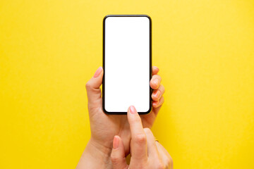 Person holding mobile phone with empty screen on yellow background