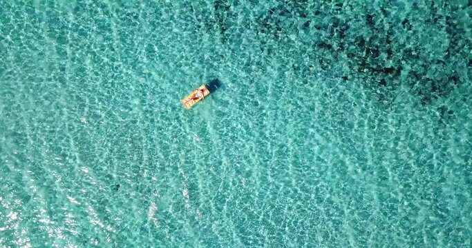 Female tourist enjoy floating on transparent blue sea water laying no a colorful inflatable lilo mattress. Summer holiday vacation people relax concept. Travel lifestyle and ocean leisure activity