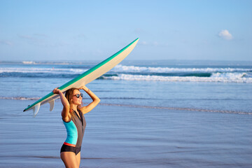 It's time for surfing! Hobby and vacation. Pretty young woman holding surf board on the sea shore.