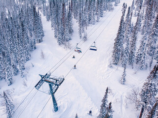 Fototapeta na wymiar Ski lifts Winter mountains with snowy forest, aerial top view