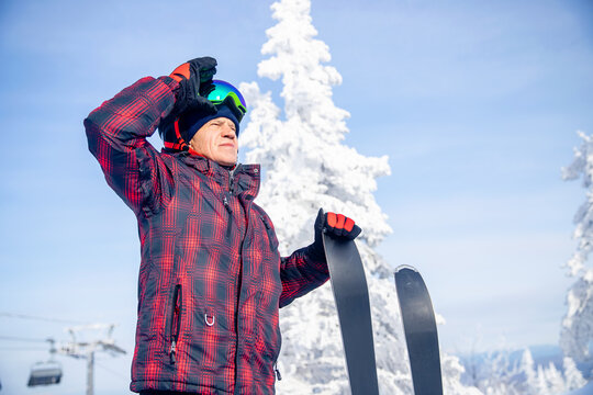 Skier senior man in activewear and helmet with ski on mountain blue sky