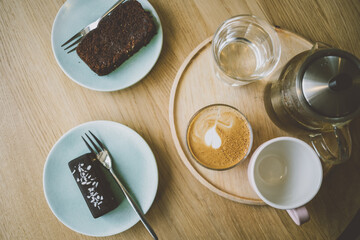 Sweet desserts and coffee tea drinks served on the table. Top view. Raw chocolate vegan bar and bite of banana bread. Cozy atmosphere. 