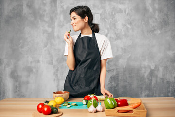 housewife in a black apron in the kitchen cutting vegetables healthy eating